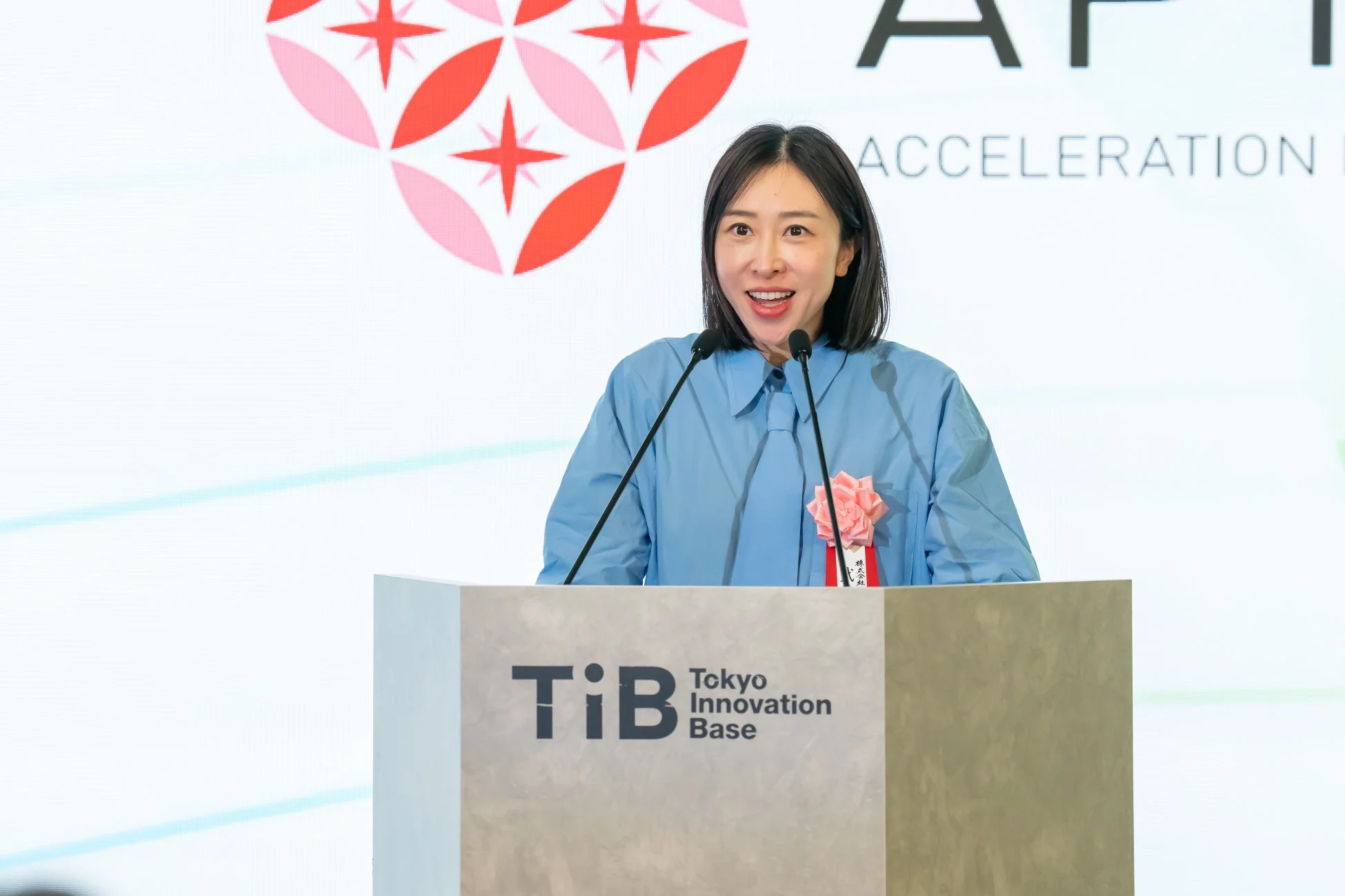 青いシャツを着て講演する女性