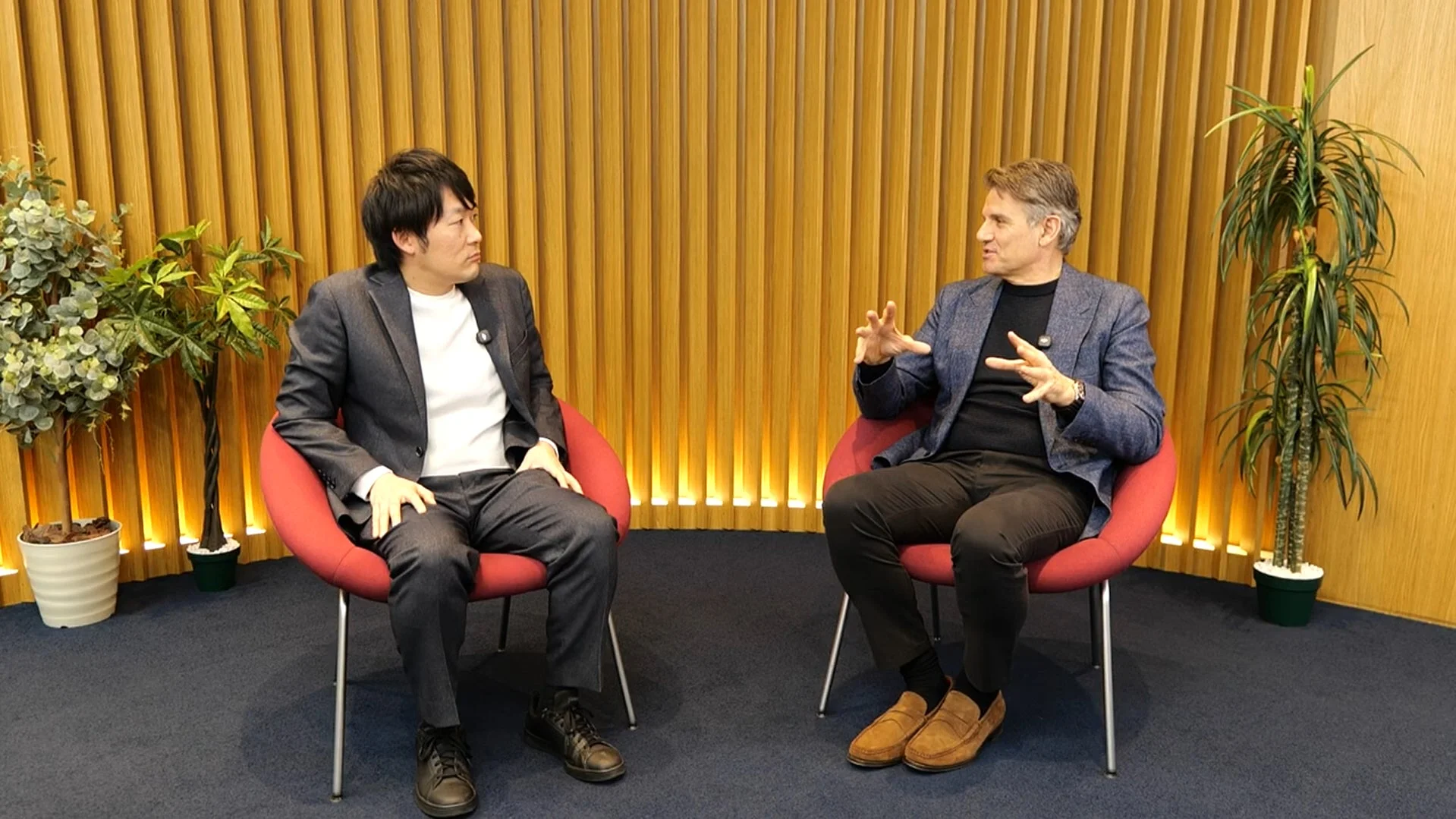 赤い椅子に座った2人の男性が対話している様子