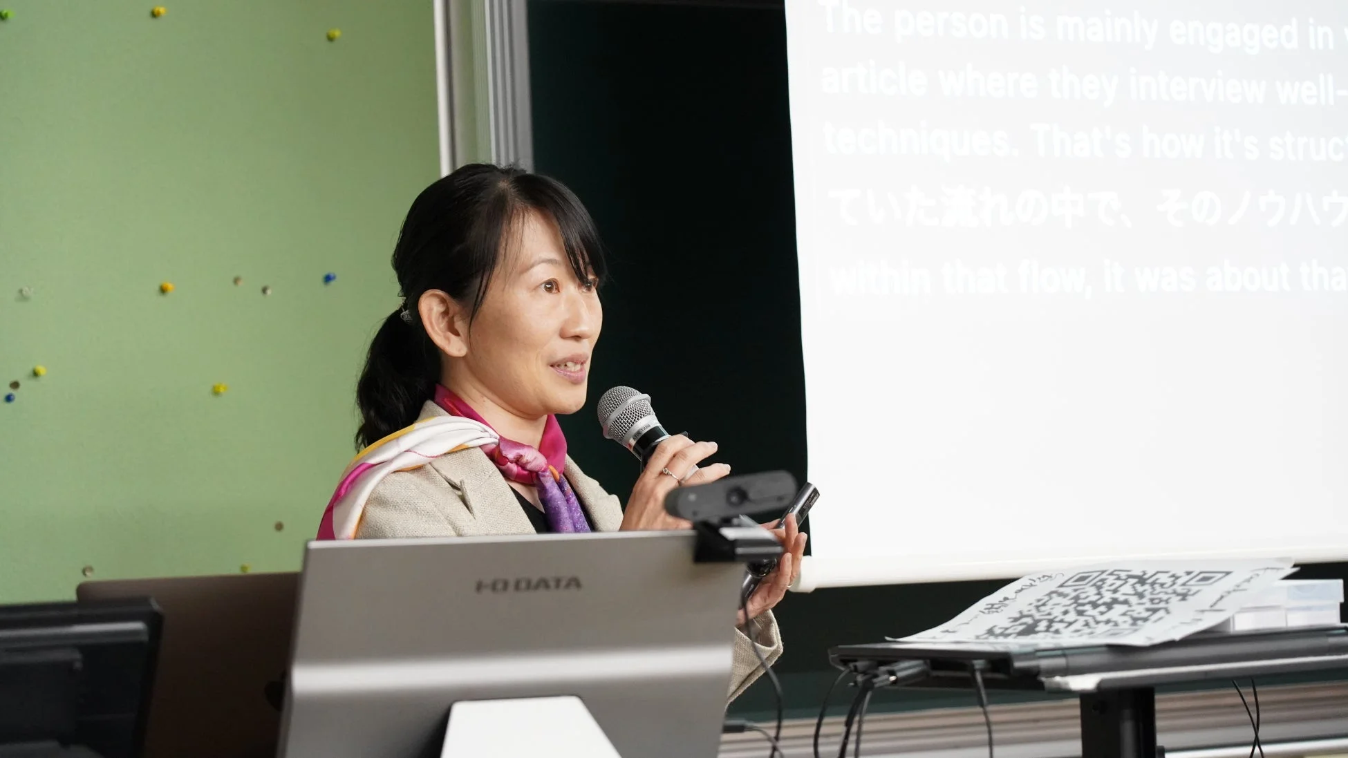 マイクを持って講演する女性の姿