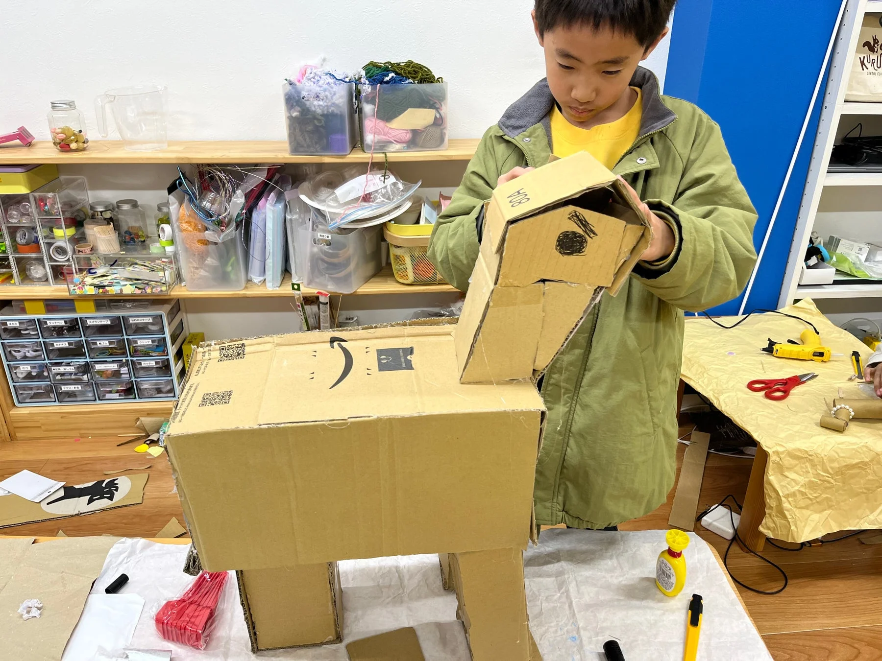 男の子がダンボールを使って大きな造形物を作っている様子。
