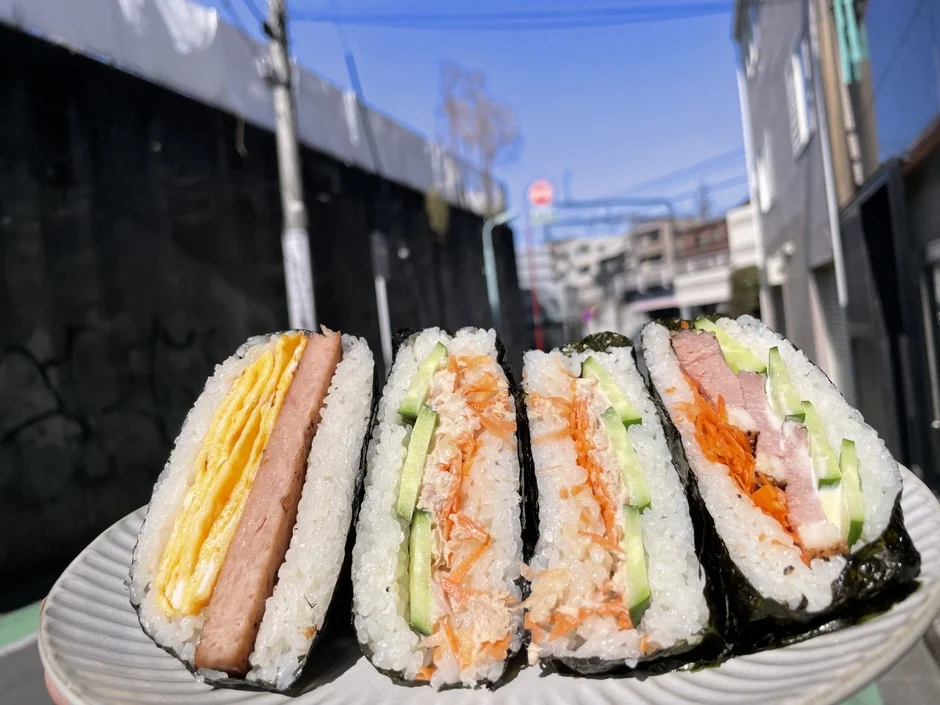 青空の下、白い皿に盛り付けられた4つの手作りおにぎり