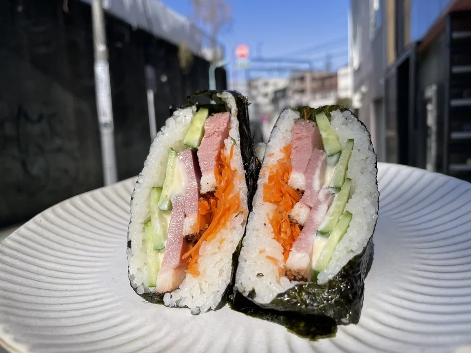 ハム、きゅうり、人参などの具材がたっぷり詰まったおにぎらずが白い皿に盛り付けられている