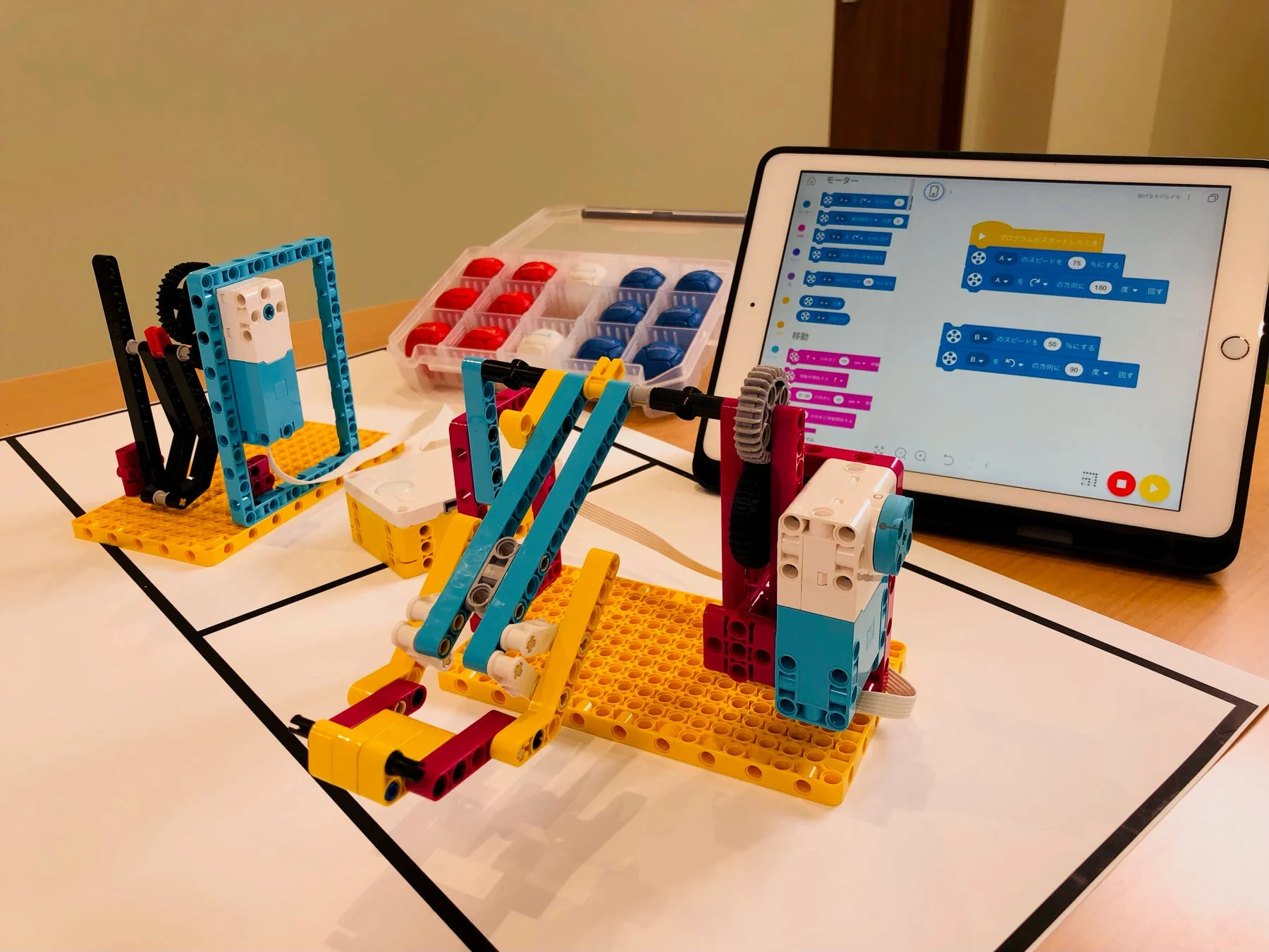 iPadでプログラミング画面を見る学生とレゴロボット