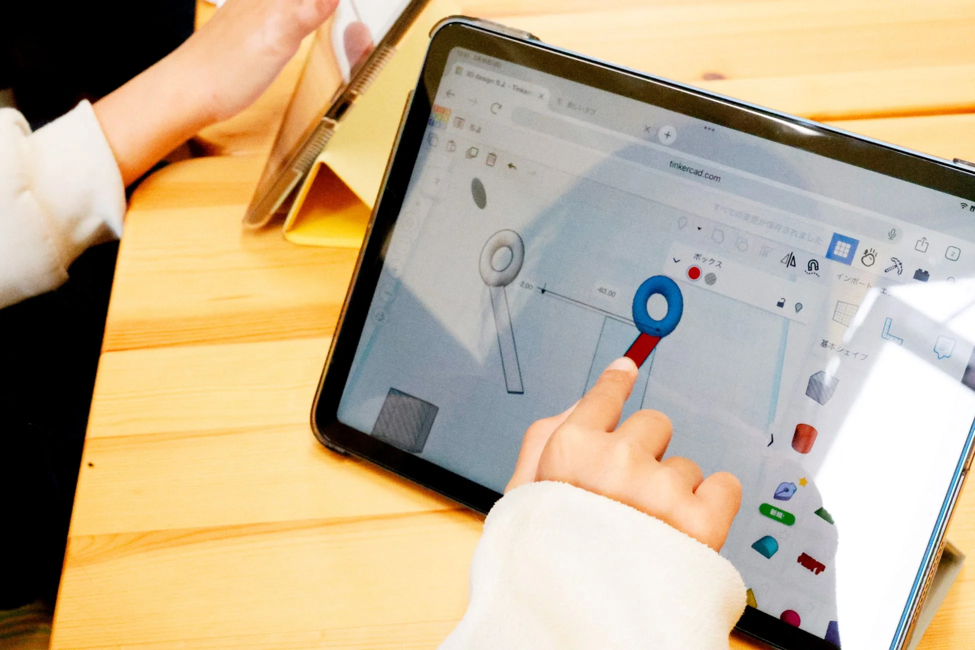 子どもがタブレット端末で3Dデザインソフトウェア「Tinkercad」を操作している様子です。