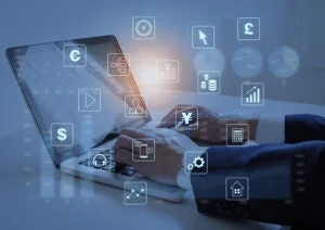 ノートパソコンを使用する人物の周りに、金融、ビジネス、データ分析などを象徴する様々なデジタルアイコンが浮かんでいる様子が描かれています