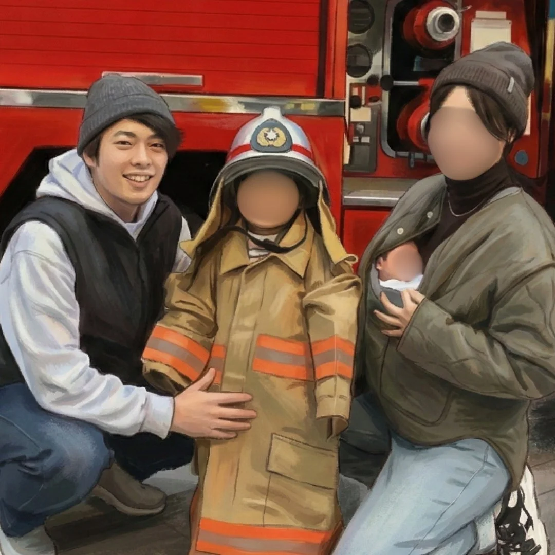 消防車を背景に、消防士の制服を着た子供と、笑顔の父親、そして赤ちゃんを抱っこした母親が写る家族写真です。楽しげな雰囲気が伝わります。