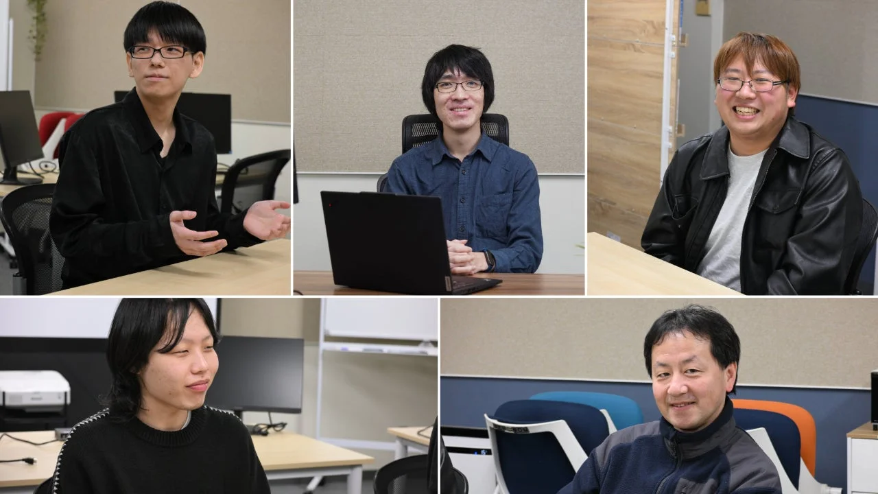 オフィスまたは会議室で5人の男性が座っています。皆笑顔で、和やかな雰囲気の中で会話しているようです。