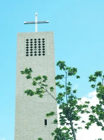 青空を背景に、十字架を頂くレンガ造りの高い塔が写っている
