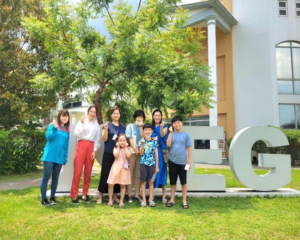 屋外で大人と子供たちが集まって笑顔でポーズをとっている集合写真