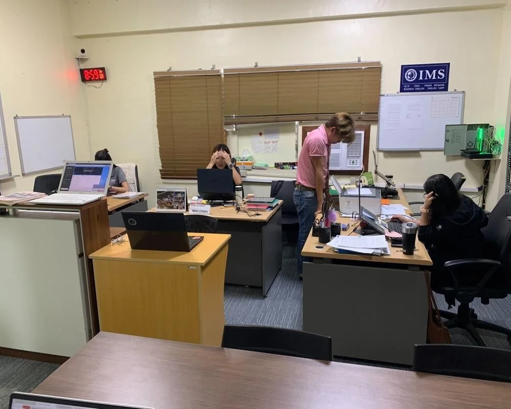 オフィスのような空間で、数人の人々がパソコンに向かって作業や学習をしている様子