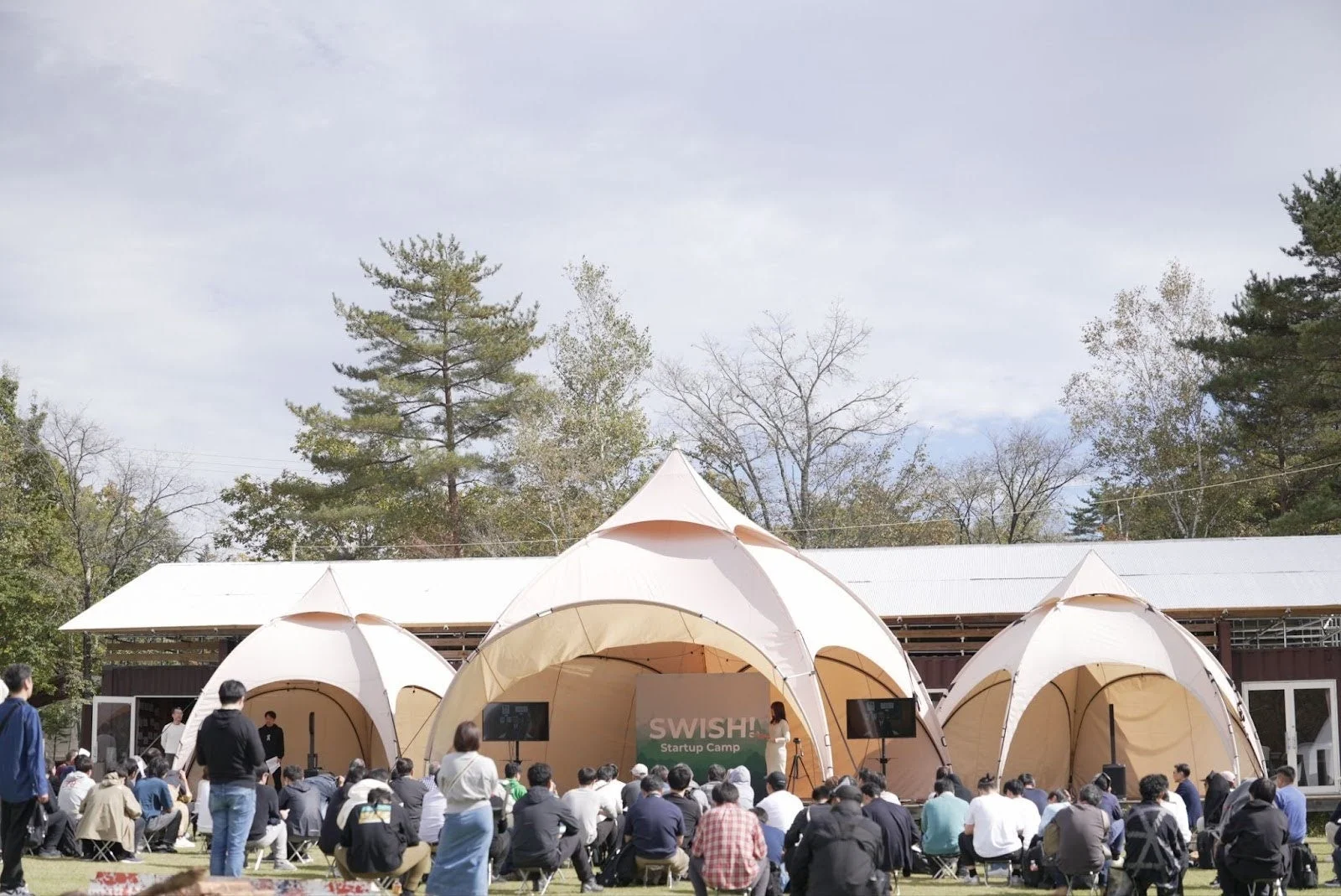 屋外で開催されたスタートアップキャンプの様子、テントの下で聴講する参加者