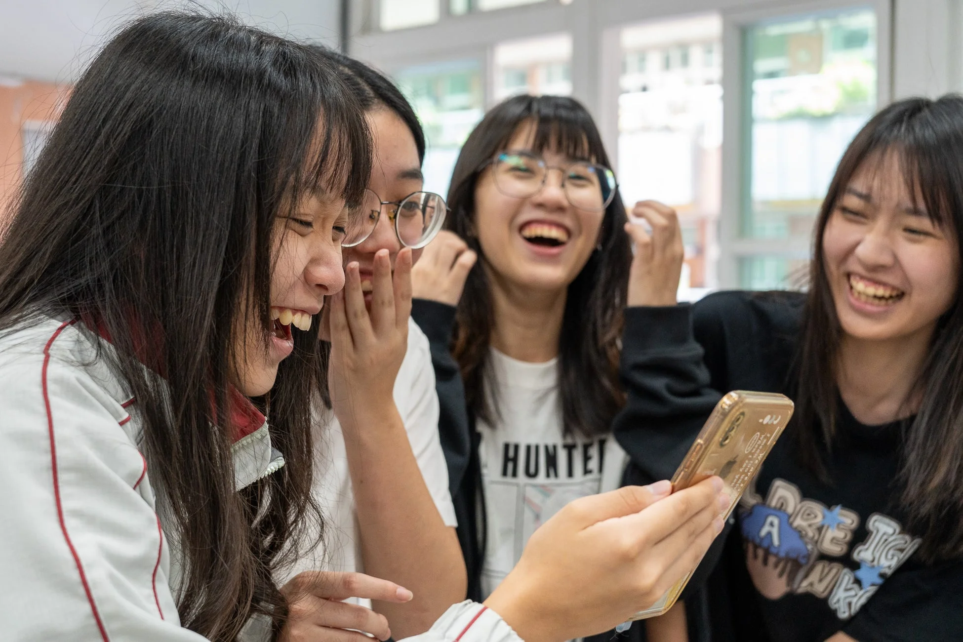 スマートフォンを見ながら楽しそうに話す女子学生たち