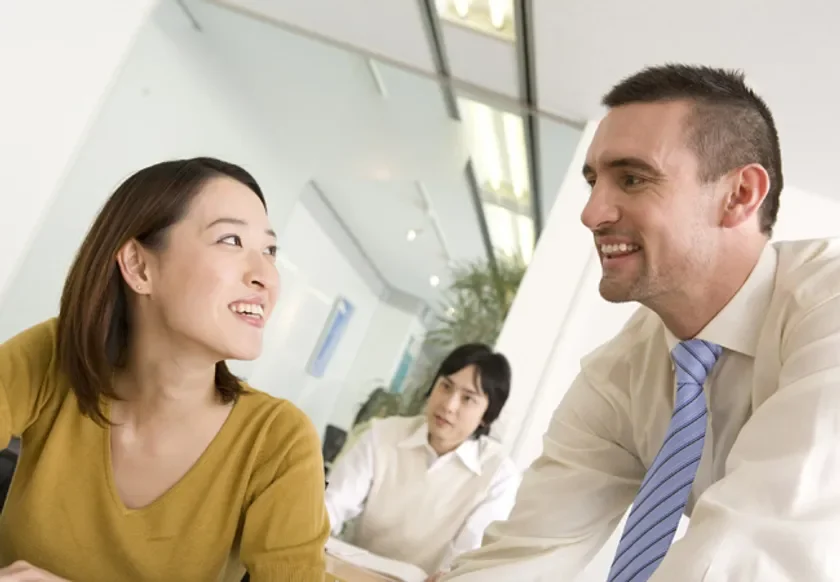オフィスで笑顔で会話する男女