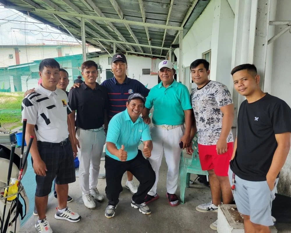 ゴルフ練習場で男性が集合写真を撮っている様子