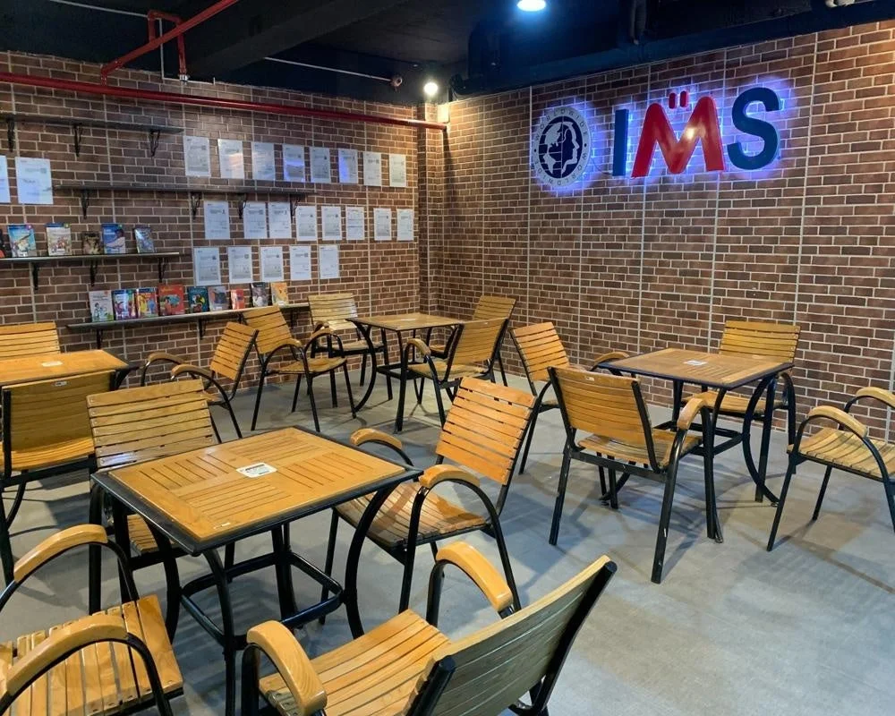 レンガ壁と木製のテーブルや椅子が並ぶ広々とした屋内スペース