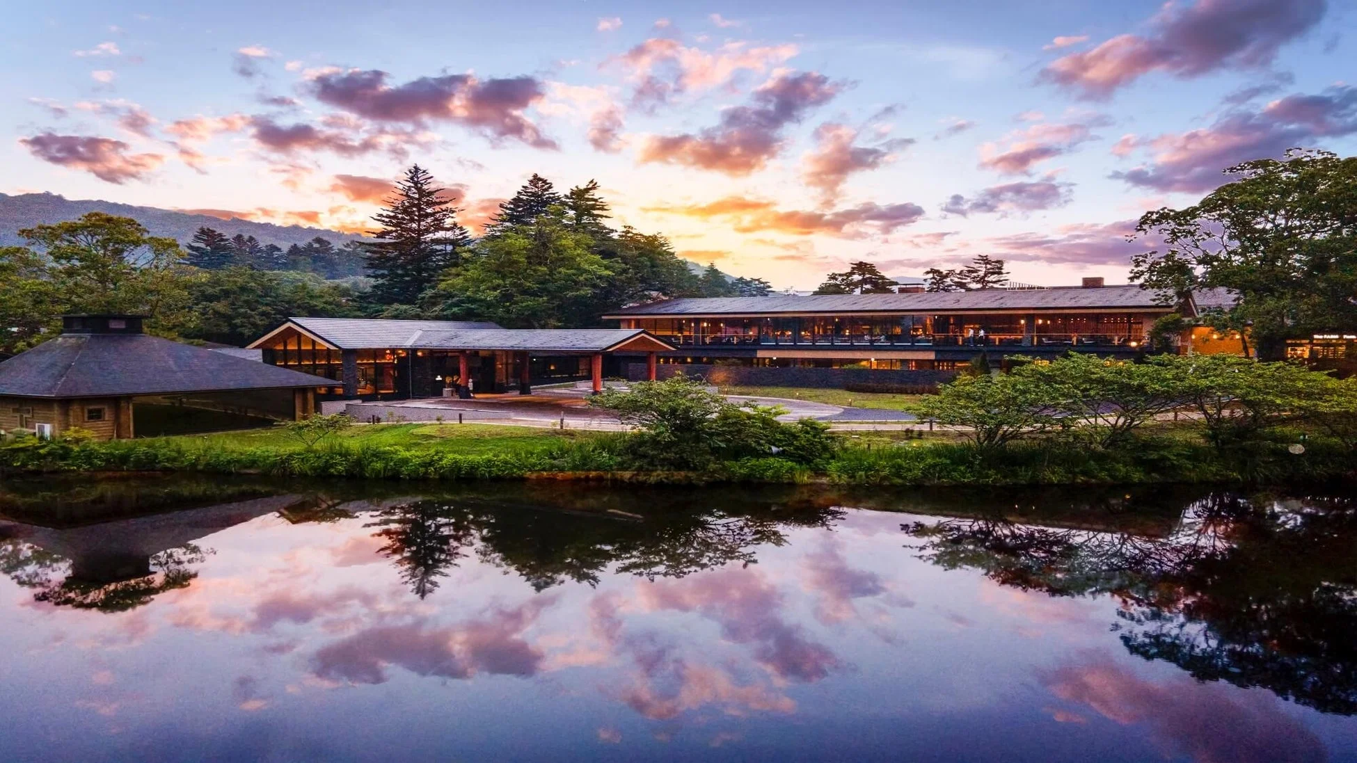 夕焼け空の下、湖畔に佇むリゾートホテルの全景