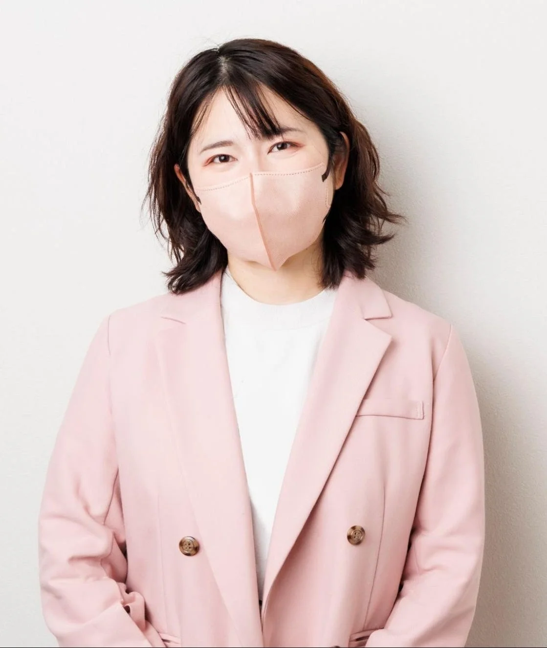 ピンクのマスクとダブルブレストのピンクのジャケットを着用した女性のポートレート