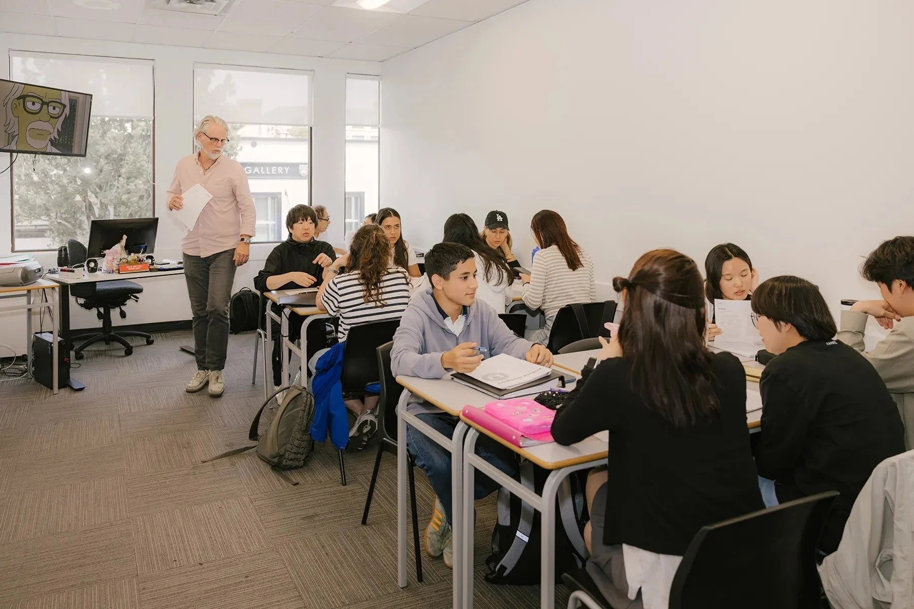 明るい教室で教師が生徒たちに話しかけている様子