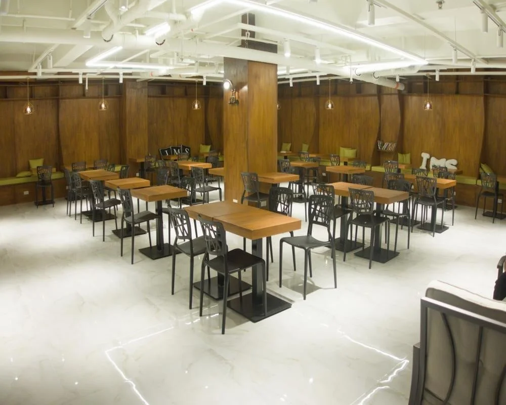 木製の壁と白い床が特徴の、広々としたモダンなカフェまたはレストランの室内