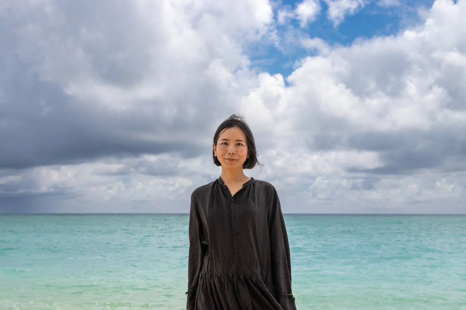 海を背景に笑顔で立つ三戸真理子氏