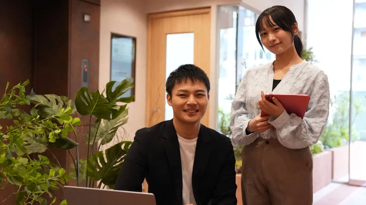 オフィスで笑顔の男女が協力している様子