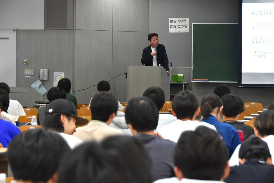 講義風景、スクリーンに株式投資の説明