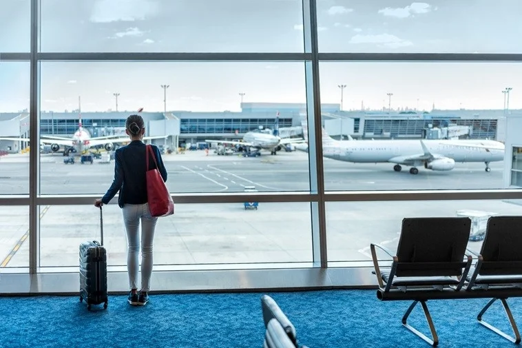 空港の窓から飛行機を眺める女性