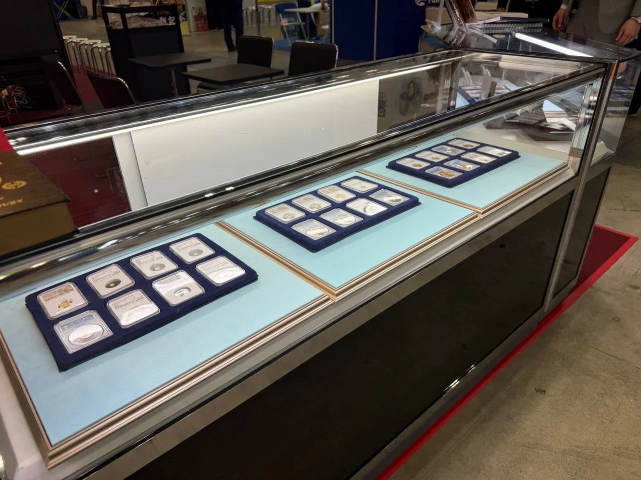 ガラス製のショーケースの中に、個別にケースに入れられた複数の収集用のコインやメダルが展示されています。