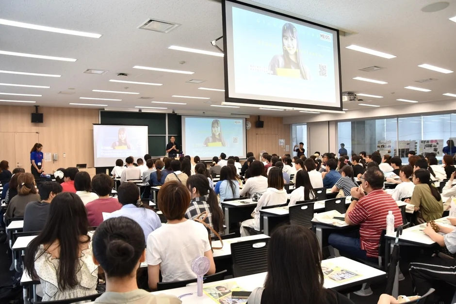 大学の講義室で、多くの学生や参加者が講演会やセミナーに参加している様子