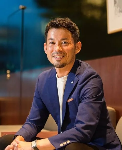 紺色のジャケットを着て笑顔を見せる男性のポートレート
