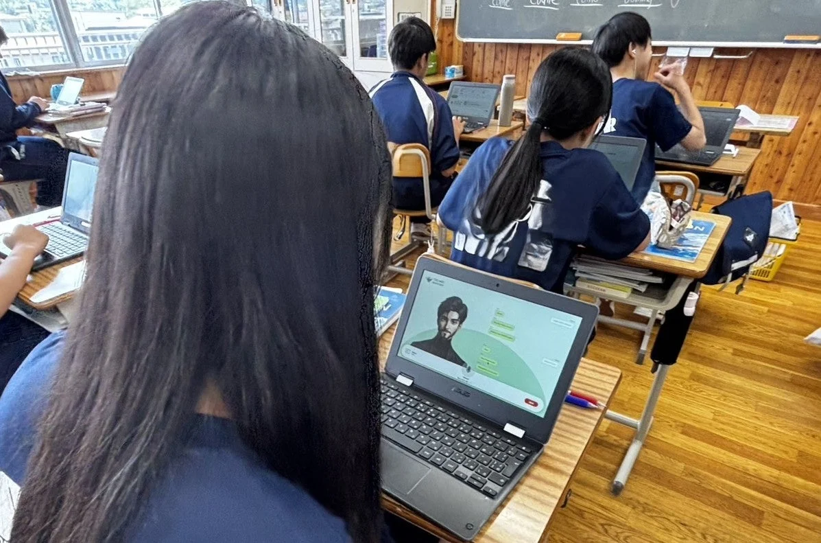 教室で生徒がノートパソコンで学習。チャットUIが表示。
