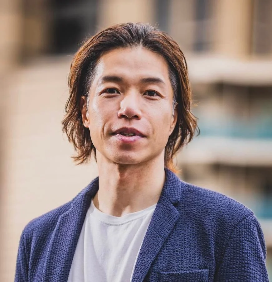 青いジャケットと白いTシャツを着た長髪のアジア人男性のポートレート