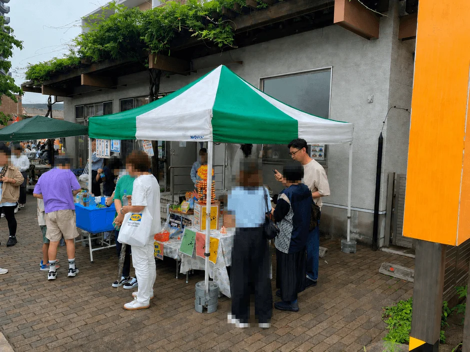 屋外の市場または屋台イベントで、人々が商品を見ている様子