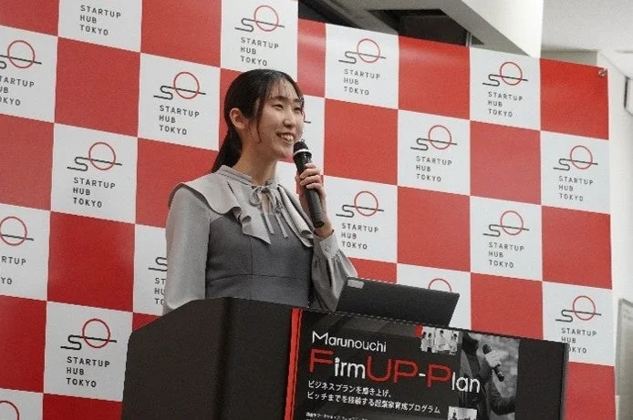 女性がマイクを持ってスピーチしている様子