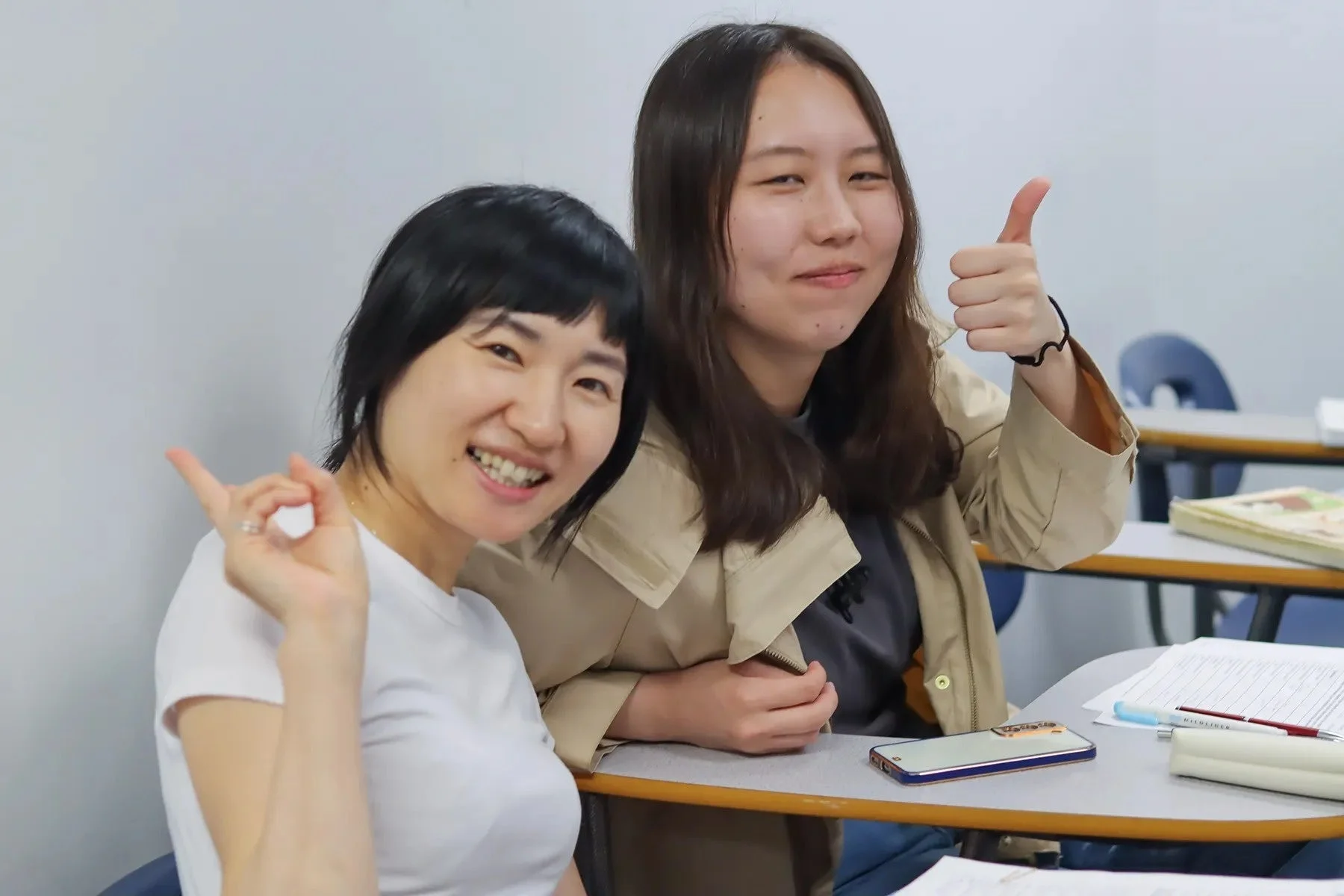 教室で女性が笑顔でポーズをとる画像