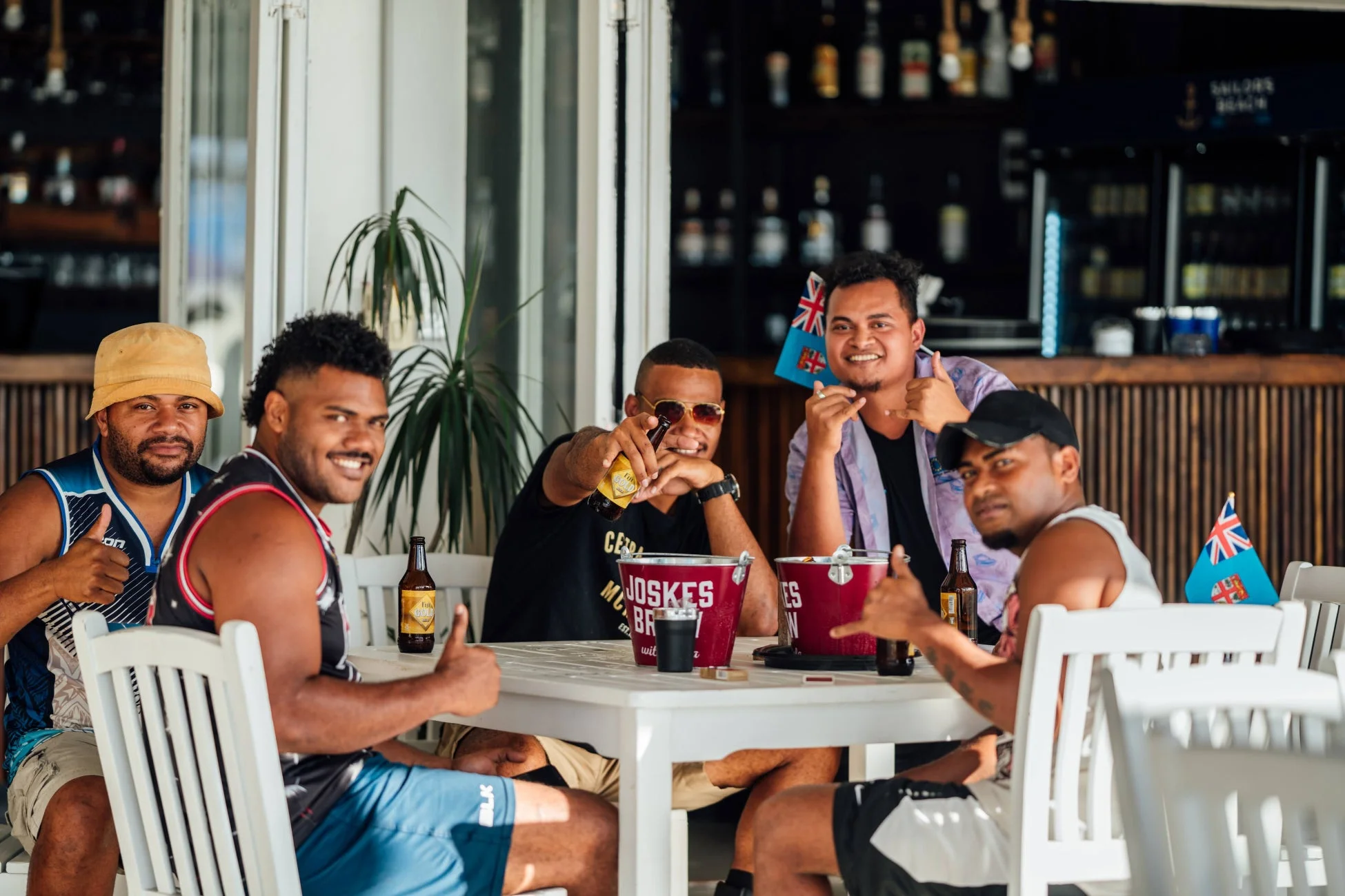 フィジーの屋外バーで、ビールを飲みながら楽しそうに談笑する男性グループ