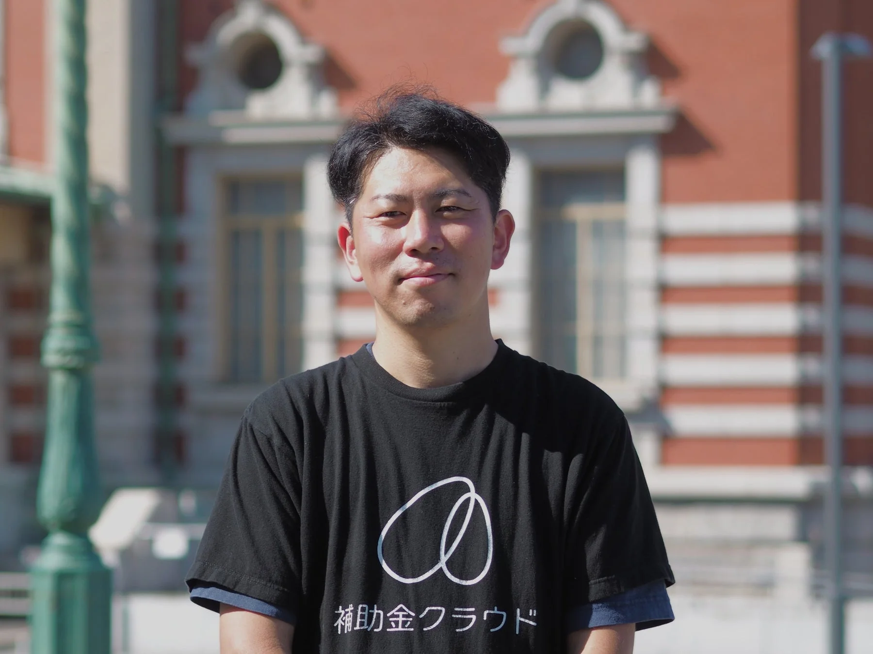 黒いTシャツを着て笑顔でカメラを見つめる佐藤淳氏