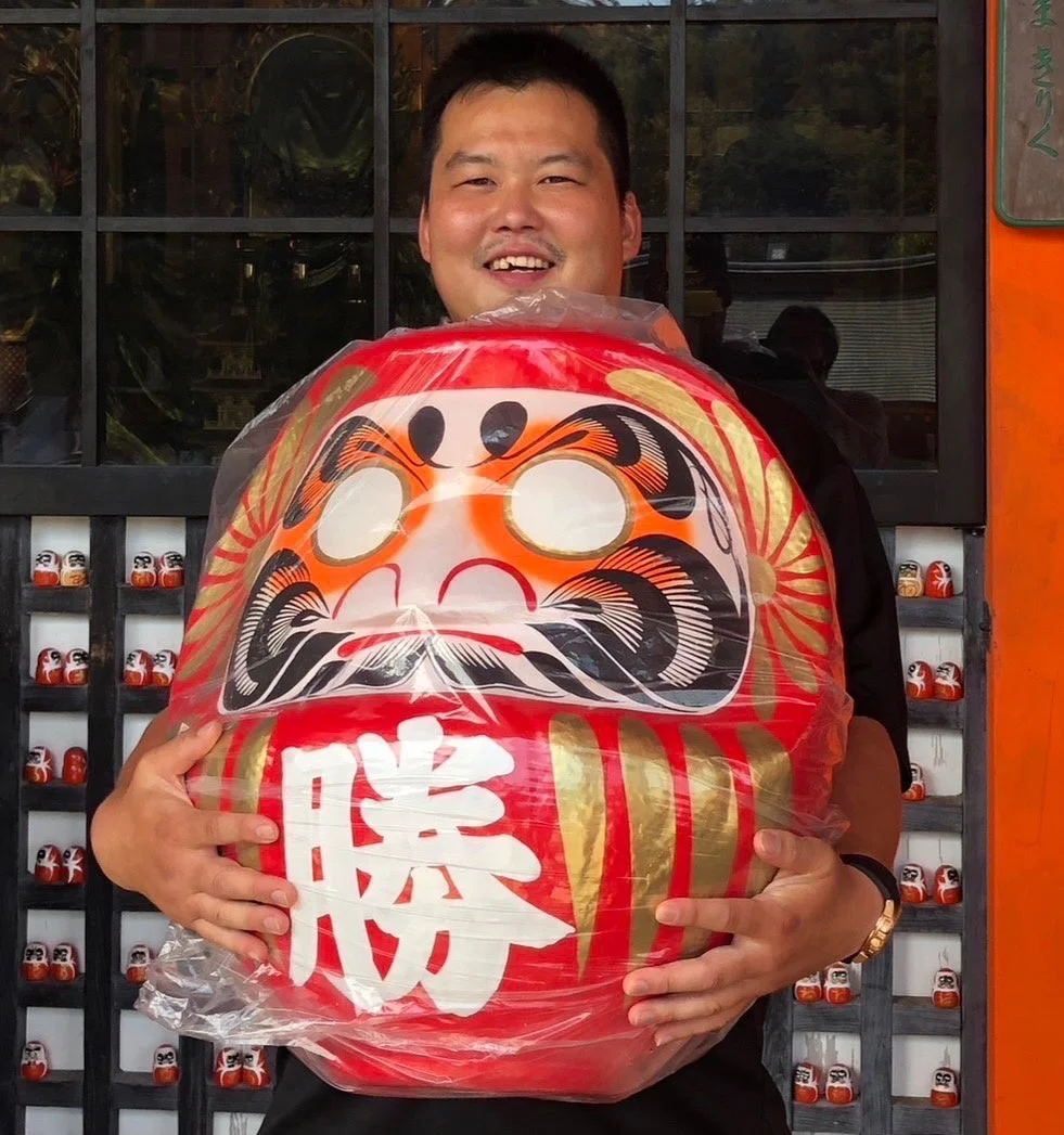 男性がだるまを抱えている画像